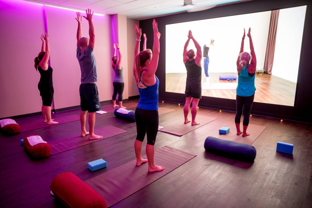 virtual fitness class on a screen in the facility with no instructors