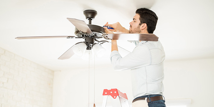 Man Adjusting Ceiling Fan With Tools