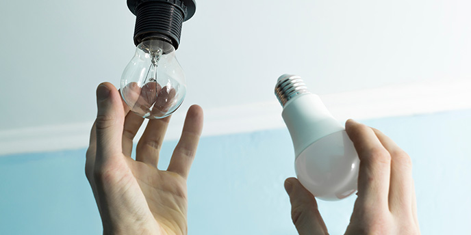 Hands Changing Old Lightbulb With LED Lightbulb